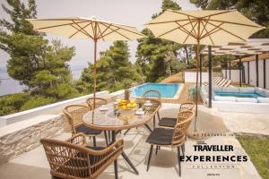 een patio met een tafel en stoelen met parasols bij Allure Luxury Villas in Skiathos-stad