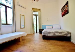 2 camas num quarto com pisos e janelas em madeira em The house at shabazi neve tzedek em Tel Aviv