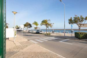 eine leere Straße neben dem Meer mit parkenden Autos in der Unterkunft Estrela do mar in Santa Luzia