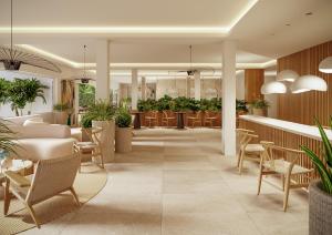 a lobby with tables and chairs and plants at Flacalco Hotel & Apartments in Cala Ratjada