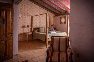 1 dormitorio con 1 cama y 1 silla en una habitación en Posada Restaurante Fuenteplateada, en Collado Hermoso
