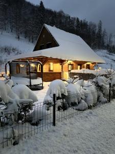 un patio cubierto de nieve con una cabaña en Chata Snezienka, en Oščadnica