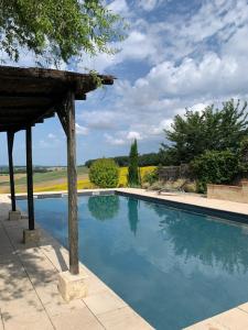 a swimming pool with a gazebo next to a field at Les 5 terrasses et sa piscine privée in La Sauvetat