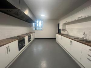 uma cozinha vazia com armários brancos e um lavatório em Marlborough Court em Hull