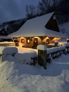 una cabaña cubierta de nieve con luces encendidas en Chata Snezienka en Oščadnica