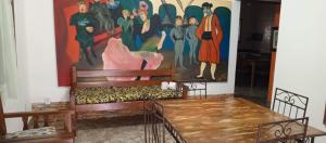 a large painting on the wall in a room with benches at casas temporada em Tiradentes do mazinho in Tiradentes