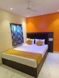 a bedroom with a large bed with orange walls at Hotel Powai Residency in Mumbai