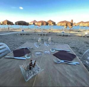 a table with wine glasses and chairs on the beach at Greta a mare in Montesilvano