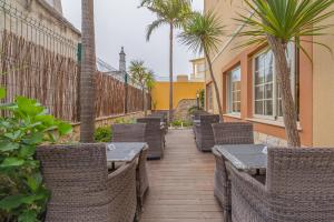 a patio with wicker chairs and tables and palm trees at Charming Residence & Guest House Dom Manuel I Adults only in Lagos