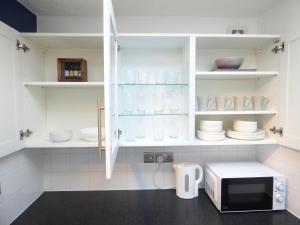 uma cozinha com armários brancos e um micro-ondas em Windmill Cottage em Ely