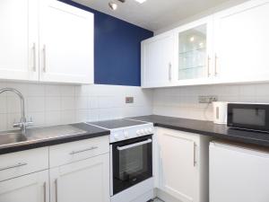 a kitchen with white cabinets and a sink and a microwave at Windmill Cottage in Ely