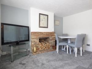 a living room with a table and a fireplace at Windmill Cottage in Ely