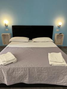 ein großes Bett mit weißer Bettwäsche und Handtüchern darauf in der Unterkunft NAPOLI VIBES Rooms in Neapel