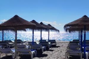 a group of chairs and umbrellas on a beach at Mijas Costa El Faro 2 Apartamento playa in Mijas