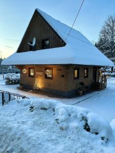 eine Blockhütte mit Schnee auf dem Dach in der Unterkunft Chata Nezábudka in Oščadnica