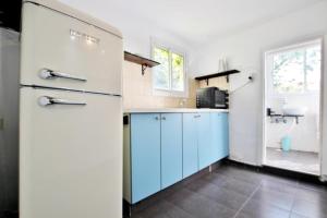 a kitchen with blue cabinets and a white refrigerator at The house at shabazi neve tzedek in Tel Aviv