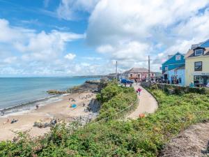 a beach with people on the sand and buildings at Y Stabl in New Quay