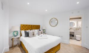 ロンドンにあるFlat 205のベッドルーム1室(大型ベッド1台、白いシーツ、鏡付)