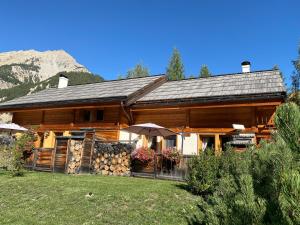 una casa di tronchi con un mucchio di tronchi davanti di Le Longet a Névache