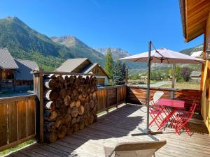 a deck with a table and a chair and an umbrella at Le Longet in Névache