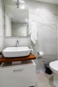 a white bathroom with a sink and a mirror at Cosy and stylish apartment in the centre in Athens