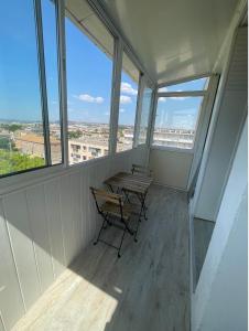 un tavolo con sedie in una stanza con finestre di Appartement proche aéroport a Marignane