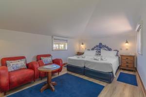 a bedroom with a bed and two red chairs at Charming Residence & Guest House Dom Manuel I Adults only in Lagos