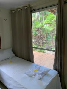 a bed in a room with a window with flowers on it at Pousada Boa Vista in Barreirinhas