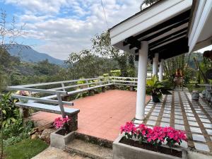 um alpendre com um banco e flores cor-de-rosa em Baan Khun Waew Rimdoi Super Cozy Guesthouse em Chiang Mai