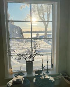 ein Fenster mit einer Vase und zwei Kerzen auf einem Tisch in der Unterkunft Bastuviken Bed and Breakfast in Uppsala