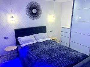 a bedroom with a bed with a blue comforter and a mirror at Uroczy Apartament z Patio in Szczecin