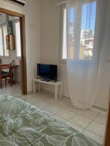 a bedroom with a bed and a tv and a window at AppArt 24 city center parking and Sea in Lignano Sabbiadoro