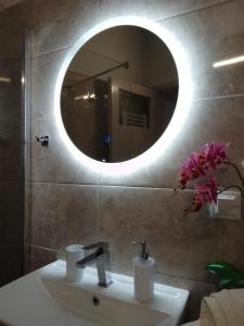 a bathroom with a sink and a round mirror at Volos Hospitality, Central Apartment in Volos