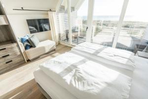 a bedroom with a white bed and a large window at Hafen27List, Haus 6 in List