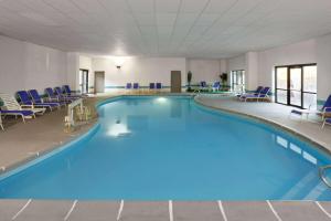 a large swimming pool in a hotel room with blue chairs at Days Inn & Suites by Wyndham Northwest Indianapolis in Indianapolis