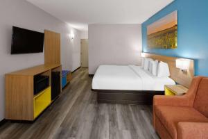 a hotel room with a bed and a couch at Days Inn & Suites by Wyndham Northwest Indianapolis in Indianapolis