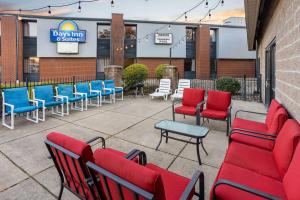 Days Inn & Suites by Wyndham Northwest Indianapolis في انديانابوليس: فناء به كراسي وطاولات حمراء وزرقاء