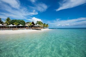 a beach with a group of umbrellas and the ocean at Castaway Island, Fiji in Castaway Island