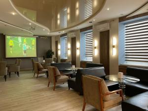 a waiting room with tables and chairs and a screen at Tengri Hotel in Atyrau