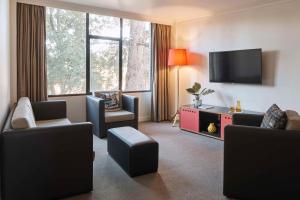 uma sala de estar com cadeiras e uma televisão de ecrã plano em Atura Albury em Albury