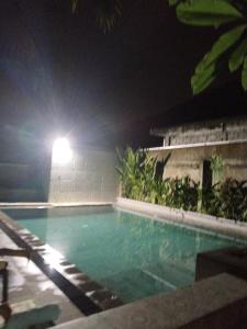 a swimming pool at night with a light on the side of a building at Dewa Bungalows in Ubud