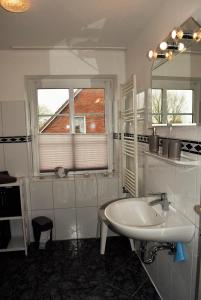 uma casa de banho branca com um lavatório e um espelho em Uthlande em Dagebüll
