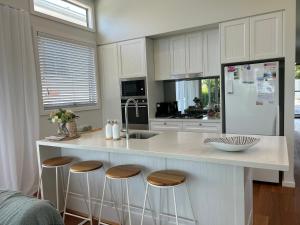 a kitchen with a counter with stools and a sink at Woonona Family Beach Villa 2 bedroom Brand new in Woonona