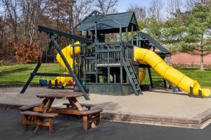 a playground with a yellow slide and picnic tables at La Quinta Inn & Suites by Wyndham Lake George in Lake George
