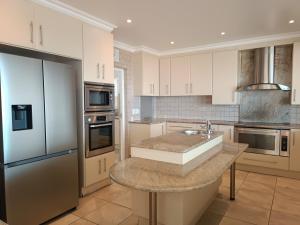 a kitchen with white cabinets and stainless steel appliances at Haven On Hill in Plettenberg Bay