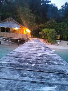 a wooden pier with a house on the beach at Raja Ampat Diva homestay in Waisai
