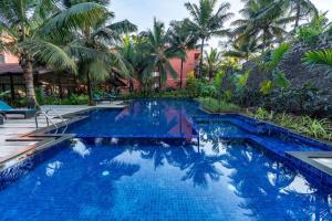 - une piscine en face d'un complexe avec des palmiers dans l'établissement Mandrem Beach Resort, a member of Radisson Individuals Retreat, à Mandrem