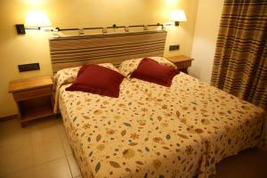 a bedroom with a bed with two red pillows at Apartamentos Mar y Sal in La Savina
