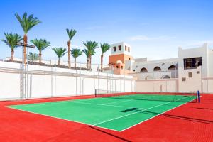 a tennis court in front of a building with palm trees at Pickalbatros Sands Port Ghalib in Port Ghalib