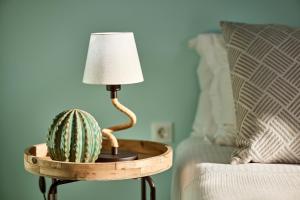 eine Lampe und ein Kaktus auf einem Tisch neben einem Bett in der Unterkunft Villa Imperial Milos in Mandrakia